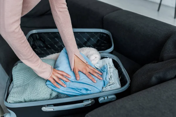 Cropped view of woman standing near suitcase while packing clothes — Stock Photo