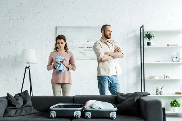 Offended man standing with crossed arms near upset woman at home — Stock Photo