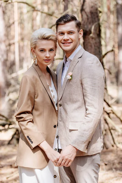 Trendy and beautiful couple holding hands in forest — Stock Photo