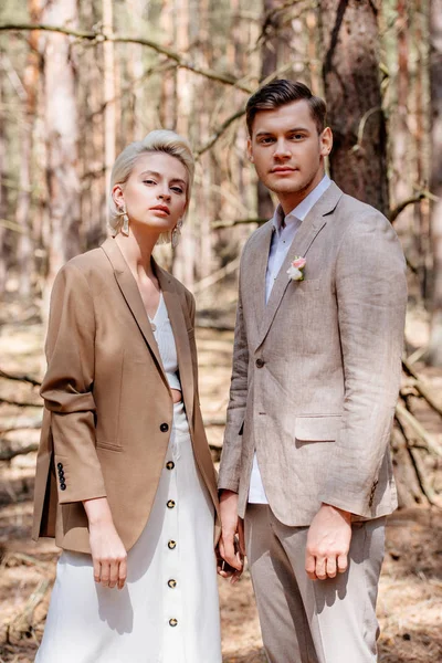 Stylish bride and bridegroom in beige clothing posing in forest — Stock Photo