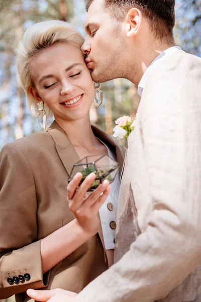 Cropped view of bridegroom kissing bride with closed eyes — Stock Photo