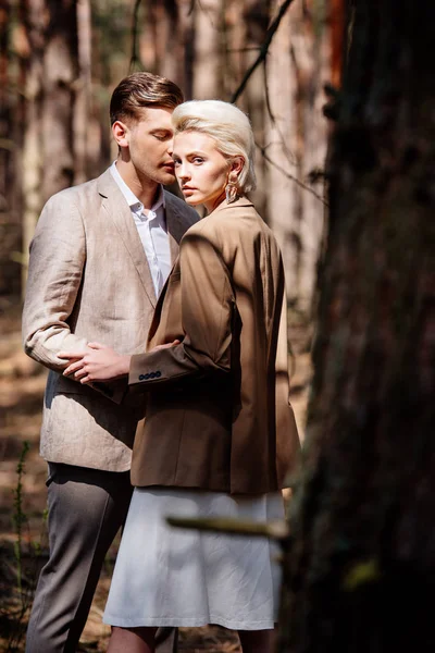 Stylish blonde woman embracing with husband in forest — Stock Photo