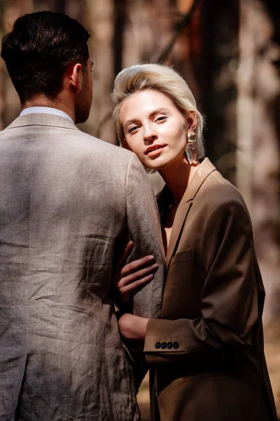 Stylish blonde young woman with husband in forest — Stock Photo