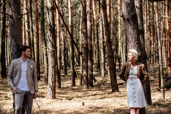 Mariée élégante et marié debout dans la forêt et en regardant l'autre — Photo de stock