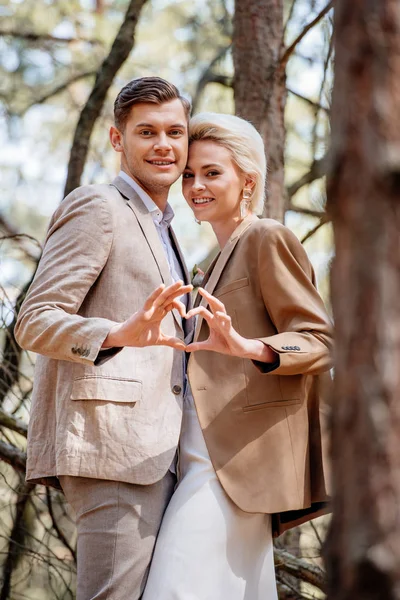 Stylisch lächelndes Paar zeigt Herzzeichen im Wald — Stockfoto