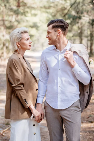 Elegante casal de mãos dadas e olhando uns para os outros na floresta — Fotografia de Stock