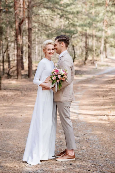 Full length view of just married couple embracing in forest — Stock Photo