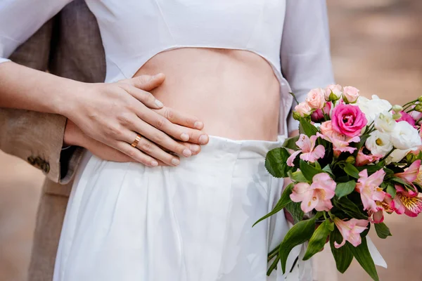 Vista cortada do noivo abraçando noiva com buquê de casamento — Fotografia de Stock