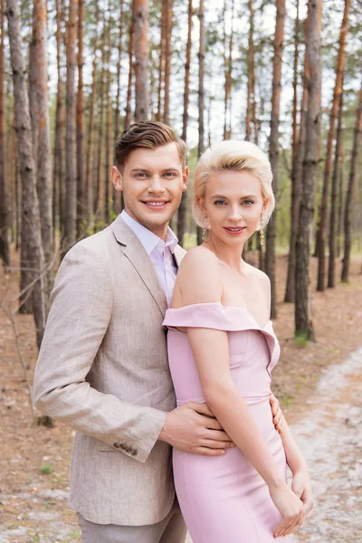 Щаслива щойно одружена пара обіймається в лісі з посмішкою — стокове фото