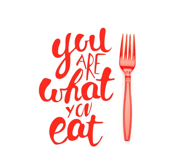 Red plastic bright fork near you are what you eat lettering isolated on white — Stock Photo
