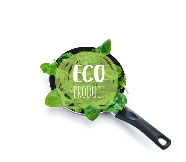 Folhas verdes de espinafre fresco na frigideira com eco produto lettering no fundo branco — Fotografia de Stock