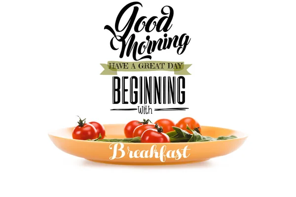 Cherry tomatoes with green spinach leaves in yellow plate with good morning, have a great day beginning with breakfast lettering above isolated on white — Stock Photo