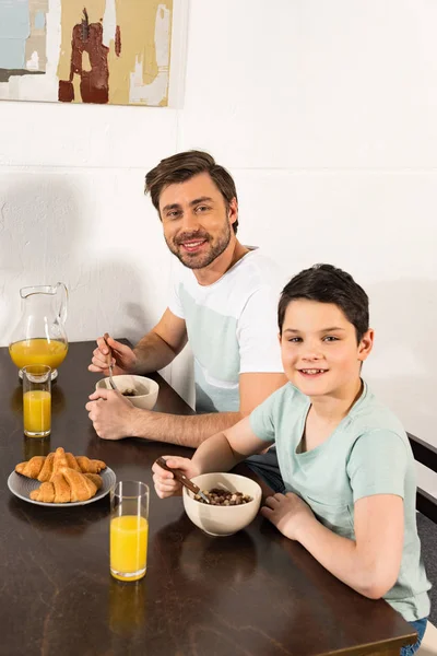 Smiling father and son having breakfast in kitchen — Stock Photo