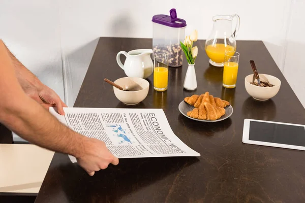 Ausgeschnittene Ansicht eines Mannes mit Zeitung während des Frühstücks in der Küche — Stockfoto