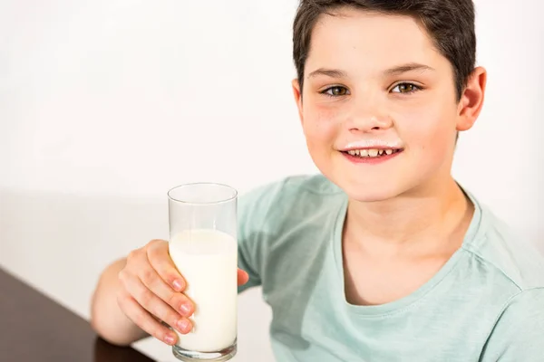 Souriant garçon tenant verre de lait et regardant la caméra — Photo de stock