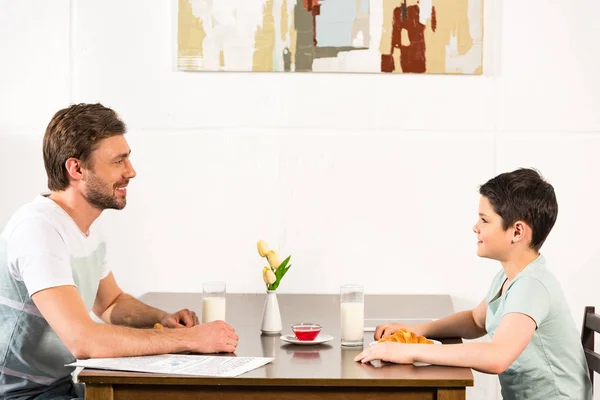Father and son looking at each other during breakfast in kitchen — Stock Photo