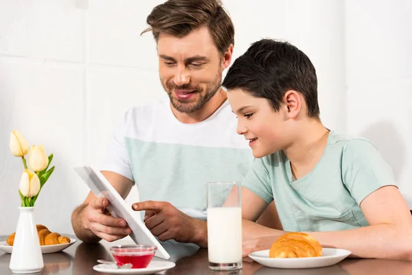 Sorridente padre e figlio utilizzando tablet digitale durante la colazione — Foto stock