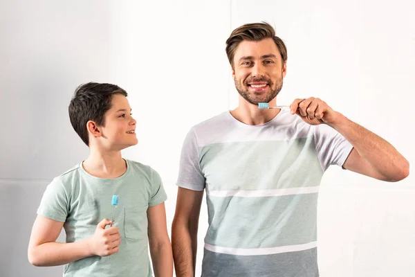 Smiling son and bearded father brushing teeth in bathroom — Stock Photo