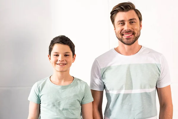 Vista frontal de sonriente hijo y papá mirando a la cámara - foto de stock