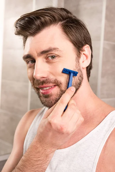 Hombre guapo barba de afeitar con afeitadora en el baño - foto de stock