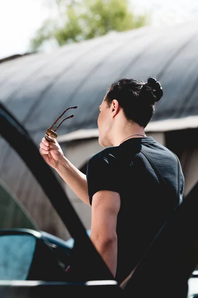 Vista posteriore di uomo elegante con occhiali da sole in posa vicino auto — Foto stock