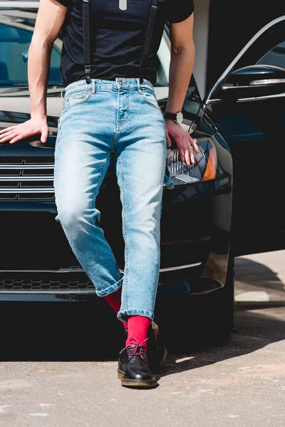 Обрезанный вид стильного мужчины в джинсе, позирующего рядом с машиной — стоковое фото