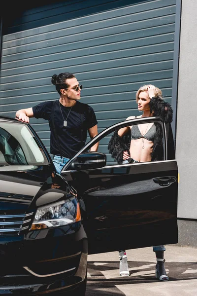 Elegante homem bonito e bela menina posando perto de carro e garagem — Fotografia de Stock