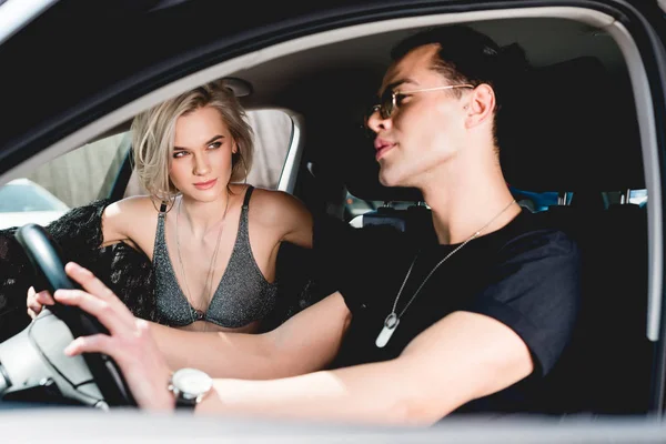 Stylish handsome man and beautiful sexy girl sitting in car — Stock Photo