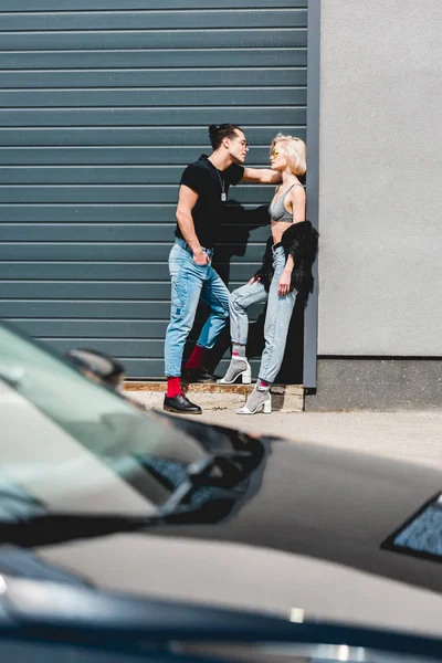 Elegante homem bonito e bela jovem posando perto da porta da garagem — Fotografia de Stock