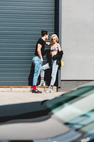 Homme élégant et sexy jeune femme posant près de la porte de garage — Photo de stock