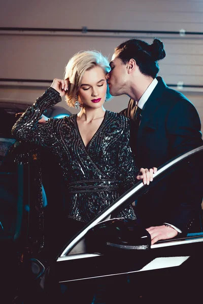 Stylish man kissing beautiful seductive woman near car — Stock Photo