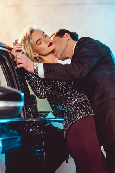 Hombre elegante besar hermosa mujer sensual cerca de coche - foto de stock