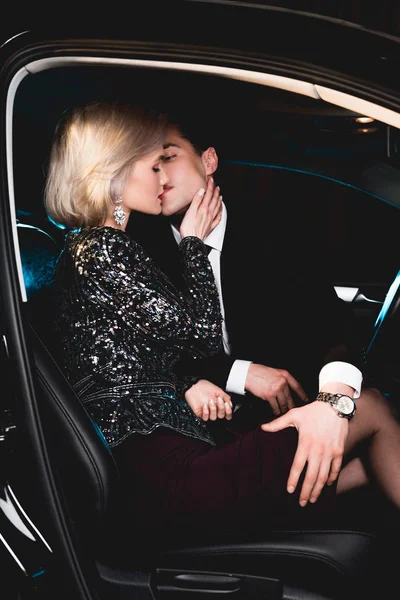 Стильный мужчина целует красивую чувственную молодую женщину в машине — стоковое фото