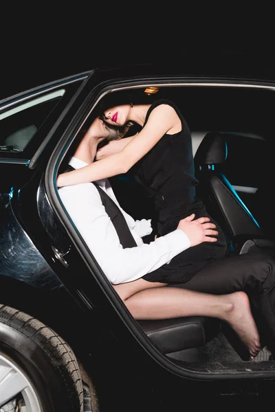 Mann und verführerische junge Frau umarmen sich im Auto — Stockfoto