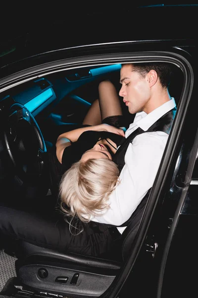 Молода жінка лежить біля стильного красивого чоловіка в машині — стокове фото