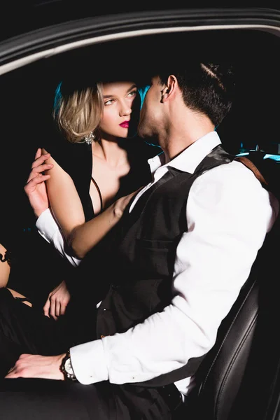 Мужчина и красивая соблазнительная молодая женщина обнимаются в машине — стоковое фото