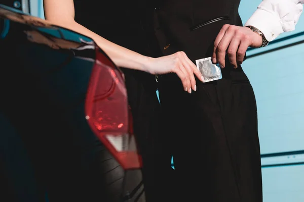 Partial view of man and woman holding condom near car — Stock Photo