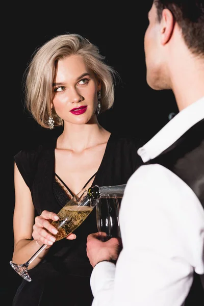 Homme versant champagne pour belle jeune femme à la mode — Photo de stock