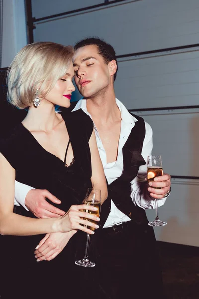 Beautiful fashionable young woman and handsome man with champagne glasses — Stock Photo