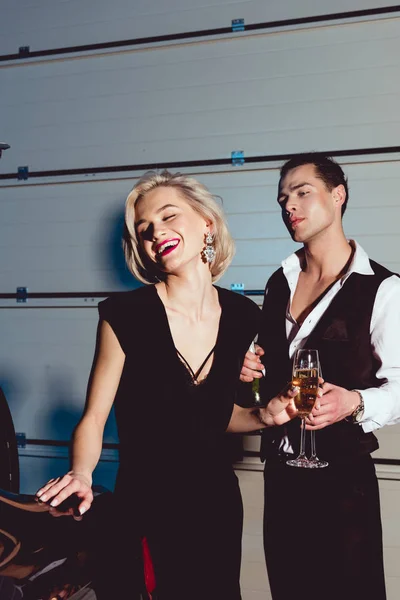 Bela mulher jovem na moda com copo de champanhe rindo perto de homem bonito — Fotografia de Stock