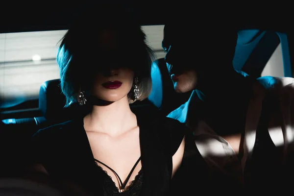 Mann und verführerische junge Frau sitzen im Dunkeln auf dem Rücksitz des Autos — Stockfoto