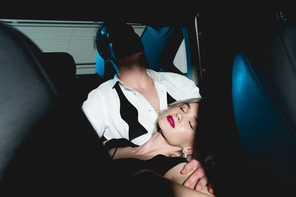 Мужчина обнимает чувственную молодую женщину на заднем сиденье машины в темноте — стоковое фото