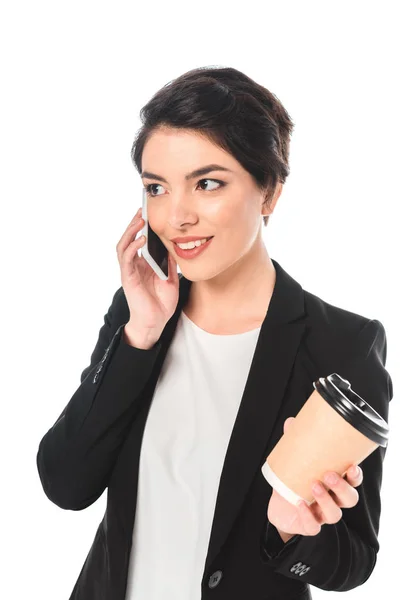 Souriant mixte femme d'affaires parlant sur smartphone et tenant tasse jetable isolé sur blanc — Photo de stock