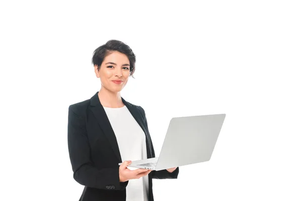 Alegre mixta carrera mujer de negocios sosteniendo portátil y sonriendo a la cámara aislado en blanco - foto de stock