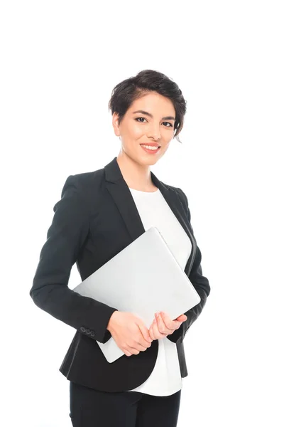 Hermosa mujer de negocios de raza mixta sosteniendo portátil y sonriendo a la cámara aislada en blanco - foto de stock