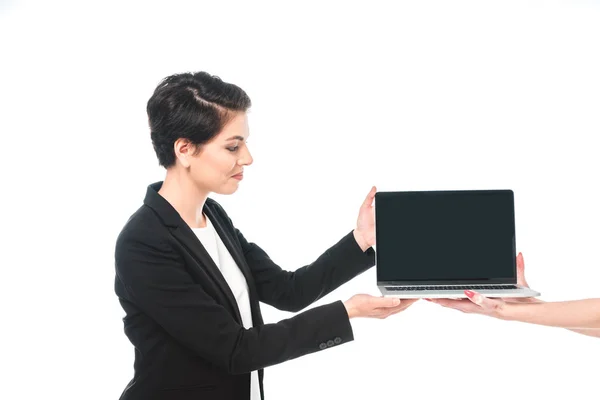 Partial view of woman taking laptop with blank screen from mixed race businesswoman isolated on white — Stock Photo