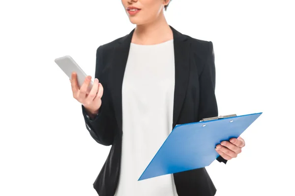 Vista parcial de la mujer de negocios de raza mixta usando teléfono inteligente y sujetando el portapapeles aislado en blanco - foto de stock