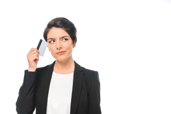 Pensativa mujer de negocios de raza mixta con tarjeta de crédito y mirando hacia otro lado aislado en blanco - foto de stock