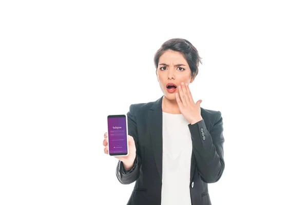 KYIV, UKRAINE - APRIL 24, 2019: Surprised mixed race businesswoman showing smartphone with Instagram app on screen isolated on white. — Stock Photo