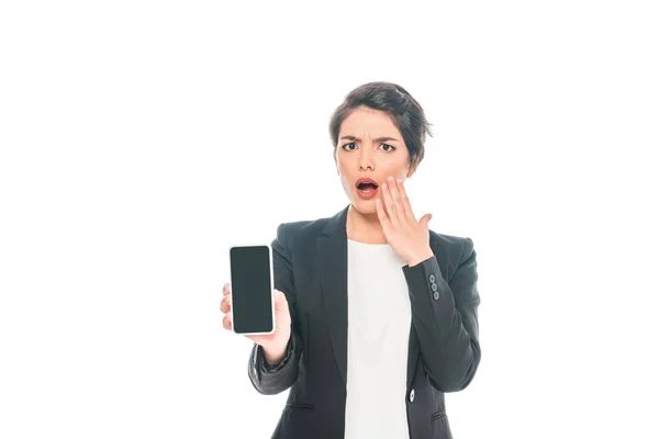 Shocked mixed race businesswoman showing smartphone with blank screen isolated on white — Stock Photo